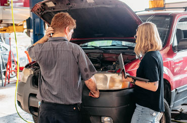 Man and woman inspecting car in a garage.