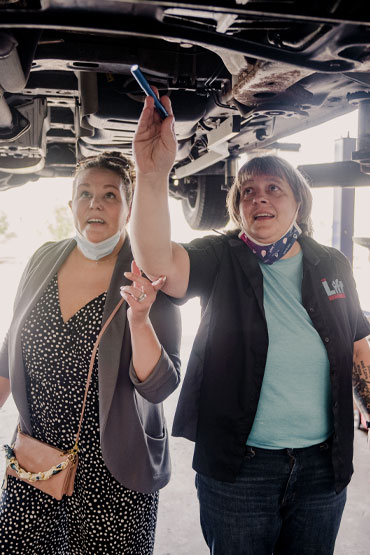 Cathy teaching a Lift Garage customer underneath her vehicle.